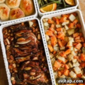 Four trays of food including dinner rolls, green beans with orange slices, roasted chicken with vegetables, and a mixed root vegetable medley on a wooden surface.