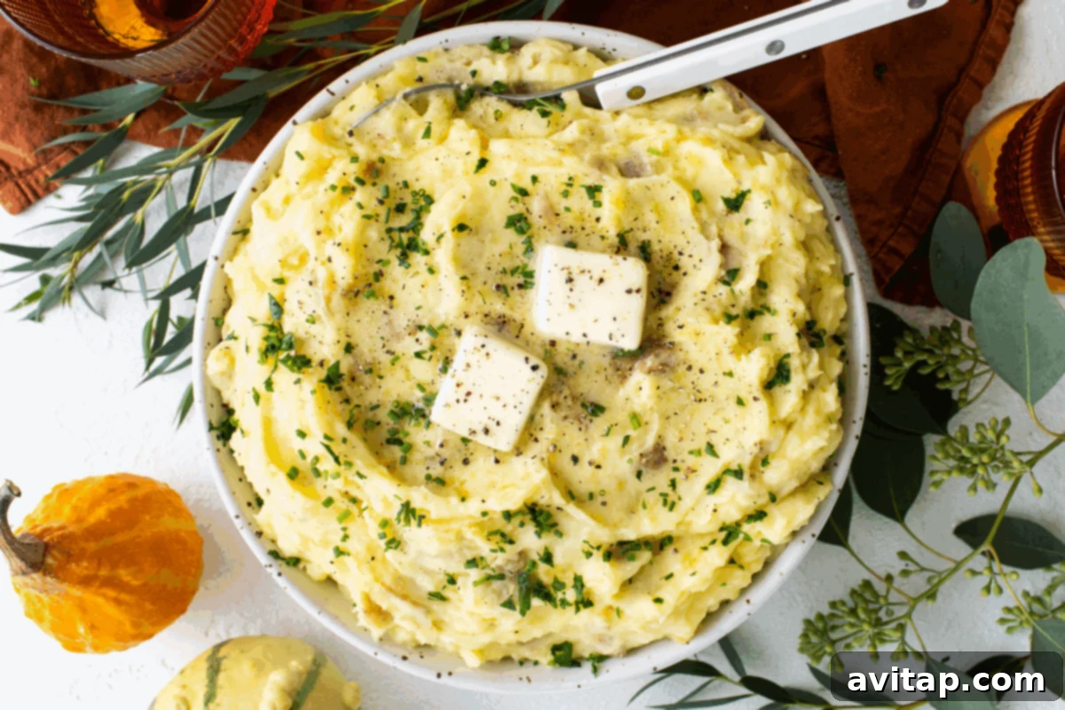 A beautifully garnished bowl of creamy mashed potatoes, topped with fresh herbs and two pats of melting butter, set against a festive autumn background. This iconic side dish is a highlight of any Thanksgiving celebration, promising comfort and indulgence.