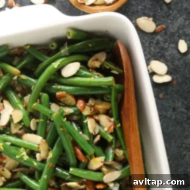 Fresh, vibrant green beans, baked to perfection in a classic casserole dish, featuring a rich, golden-brown topping. The dish is invitingly ready for a festive meal, promising comforting flavors.