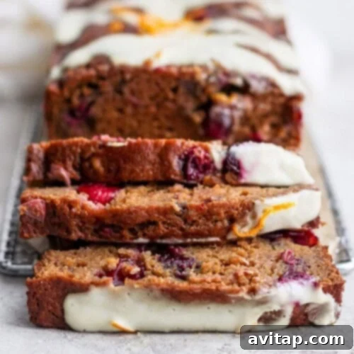 A beautifully baked loaf of cranberry orange bread, elegantly topped with a delicate drizzle of sweet icing. The bread exudes festive flavors, adorned with vibrant cranberries and subtle orange zest, inviting a delightful taste.
