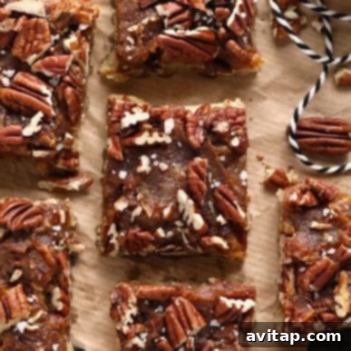 Delicious pecan pie bars, featuring a rich, nutty topping and a perfectly flaky crust, neatly arranged on a piece of parchment paper. These inviting bars are ready to be served, promising a delightful treat.