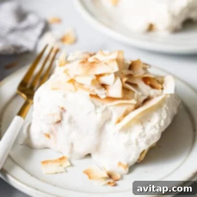 A delightful piece of coconut cream pie bar, showcasing its luscious layers of creamy coconut filling and a perfectly golden, crumbly crust. The bar is elegantly placed on a white plate, invitingly ready to be savored, promising a taste of tropical bliss.