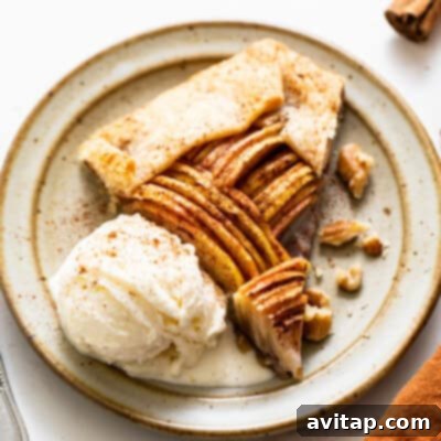 A rustic yet elegant slice of brown butter apple galette, beautifully showcasing a flaky, golden crust and tender, caramelized apple slices. The dessert is served on a white plate, subtly enhanced with a hint of warm spices, promising a comforting taste.