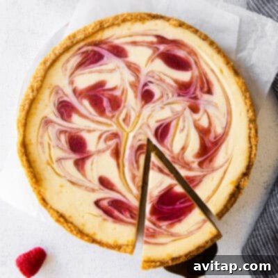 A beautifully presented healthy cheesecake, featuring a remarkably smooth, creamy filling and a delicious, sturdy crust. The dessert is elegantly garnished with fresh, vibrant raspberries and a delicate swirl of homemade raspberry sauce, inviting immediate indulgence.