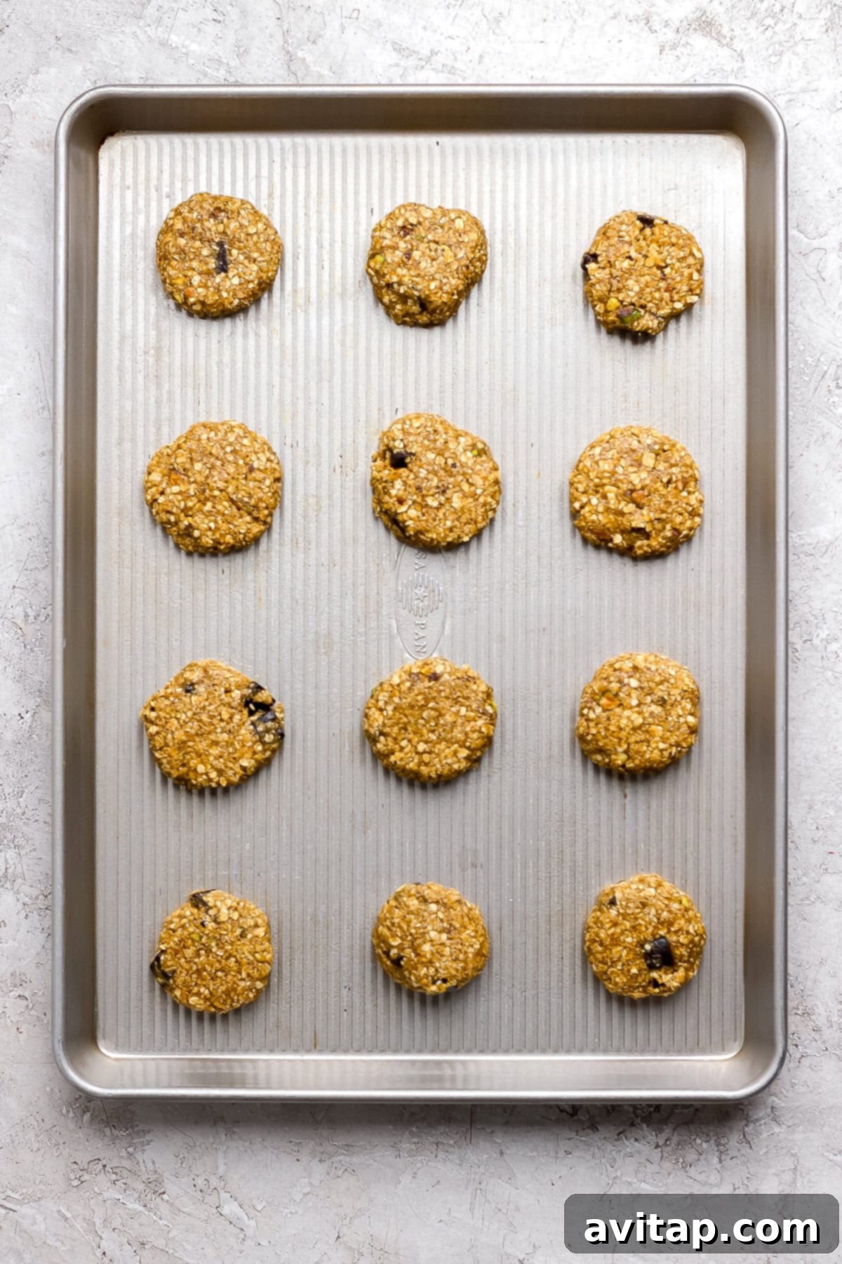 Chocolate Pistachio Dream Cookies 5 Unbaked oatmeal cookies with chocolate chips on a baking sheet.