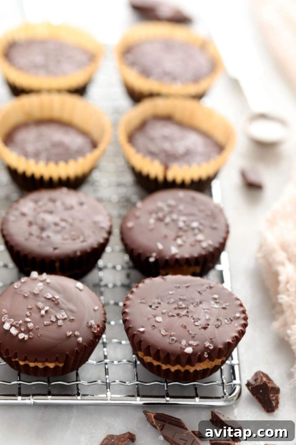 Homemade almond butter cups are a simple dessert that will satisfy your sweet tooth craving! Plus, these almond butter cups are topped with flakey sea salt. almond butter cups cooling on a metal rack after being removed from muffin tin