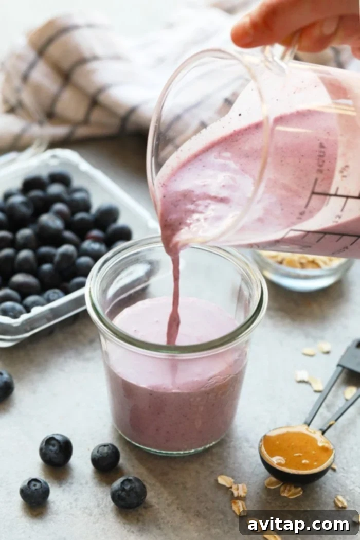 Smoothie being poured from a blender into a glass.
