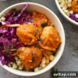 Two bowls with red curry meatballs and cabbage salad, ready to serve.