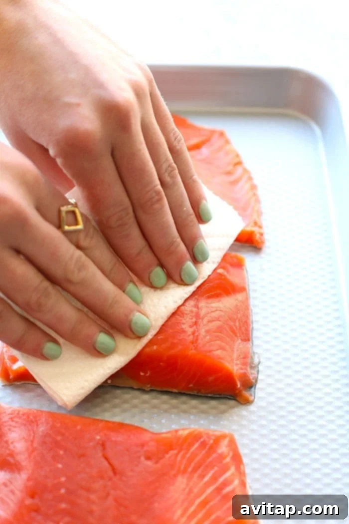 Whip up this amazing Honey Sriracha Salmon in just 8 minutes. All you need are 4 ingredients, and your oven broiler to make this protein-packed dinner that everyone will love! Chef's hands patting salmon fillets dry with paper towels for optimal cooking.