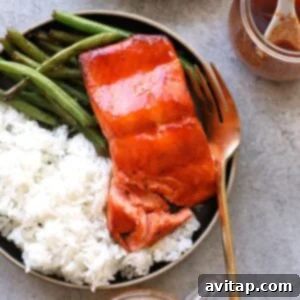 honey sriracha salmon on plate with rice and green beans and fork