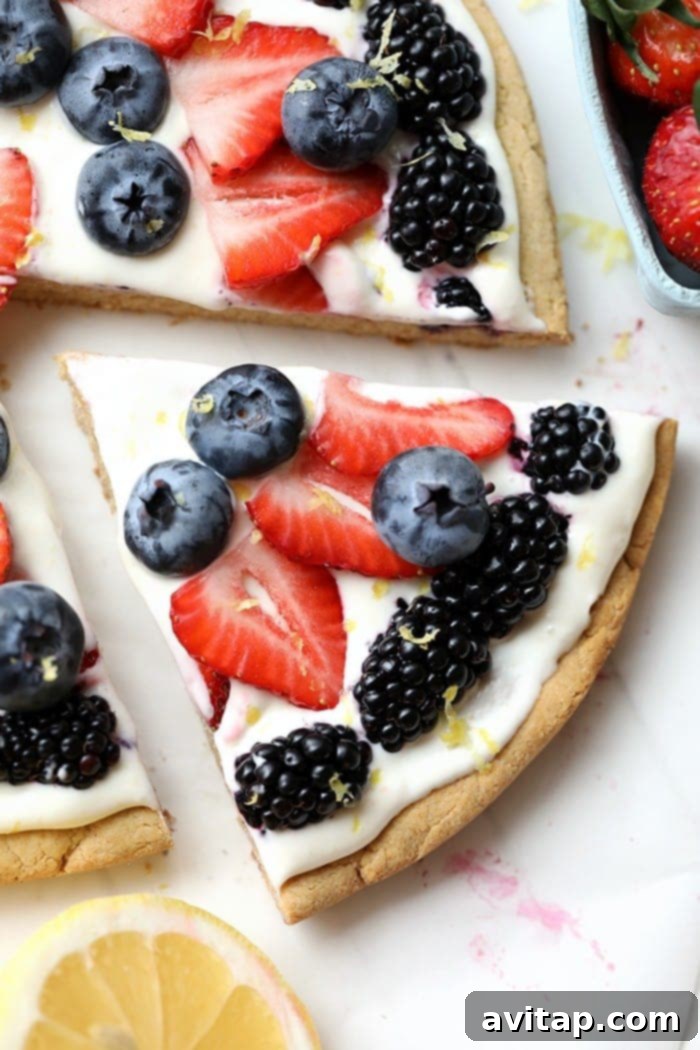 A vibrant slice of healthy fruit pizza, showcasing its colorful fruit toppings and creamy white filling.