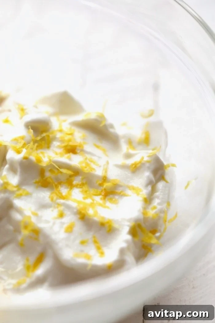 A bowl filled with creamy Greek yogurt, adorned with fresh lemon zest, ready for mixing into the fruit pizza filling.