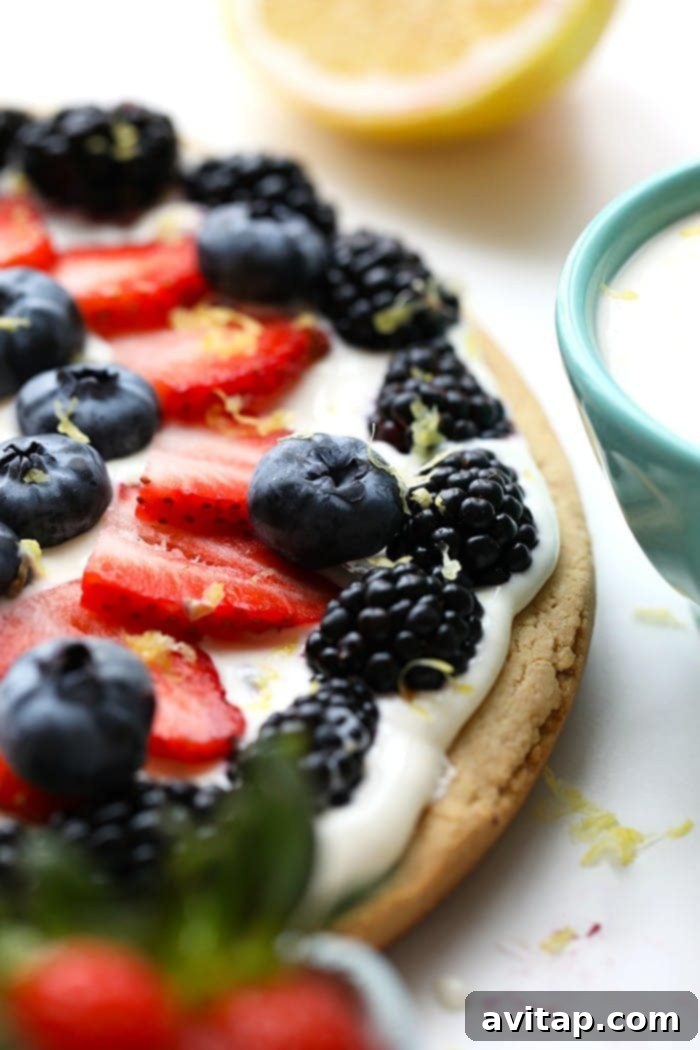 A beautifully decorated healthy fruit pizza with an assortment of fresh berries and lemon zest, ready to be served.