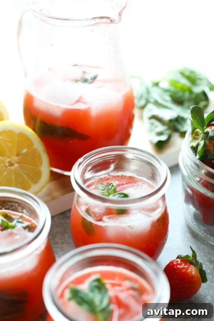Homemade strawberry basil lemonade in elegant glasses, garnished with fresh basil leaves and strawberry slices, ready to be enjoyed on a sunny day.