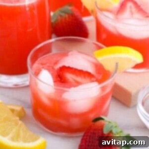 A glass of vibrant strawberry vodka lemonade, garnished with fresh fruit and herbs.