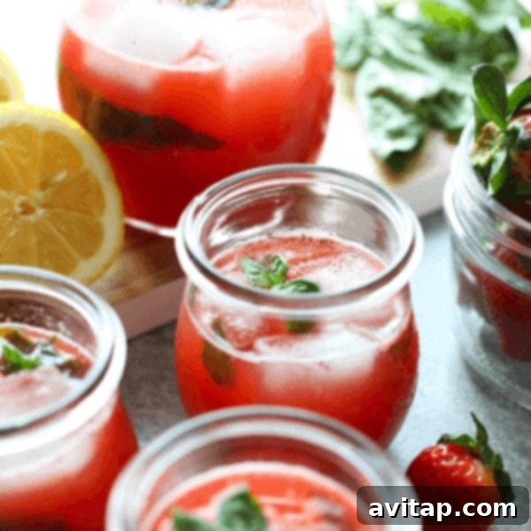 A glass of vibrant strawberry basil lemonade, garnished with fresh basil and strawberry slices, ready for a refreshing sip.