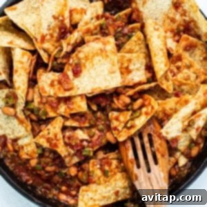 Mixing tortilla chips into sauce in a skillet.
