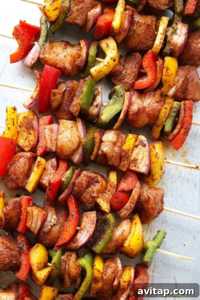 raw chicken kabobs on countertop with spices.