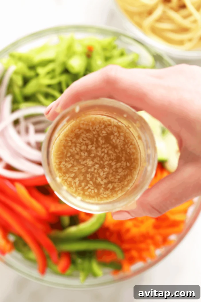 Homemade Asian sesame dressing in a mason jar, ready to be poured over the noodle salad.