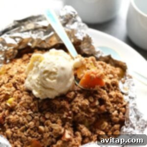 peach crumble in foil with spoon.