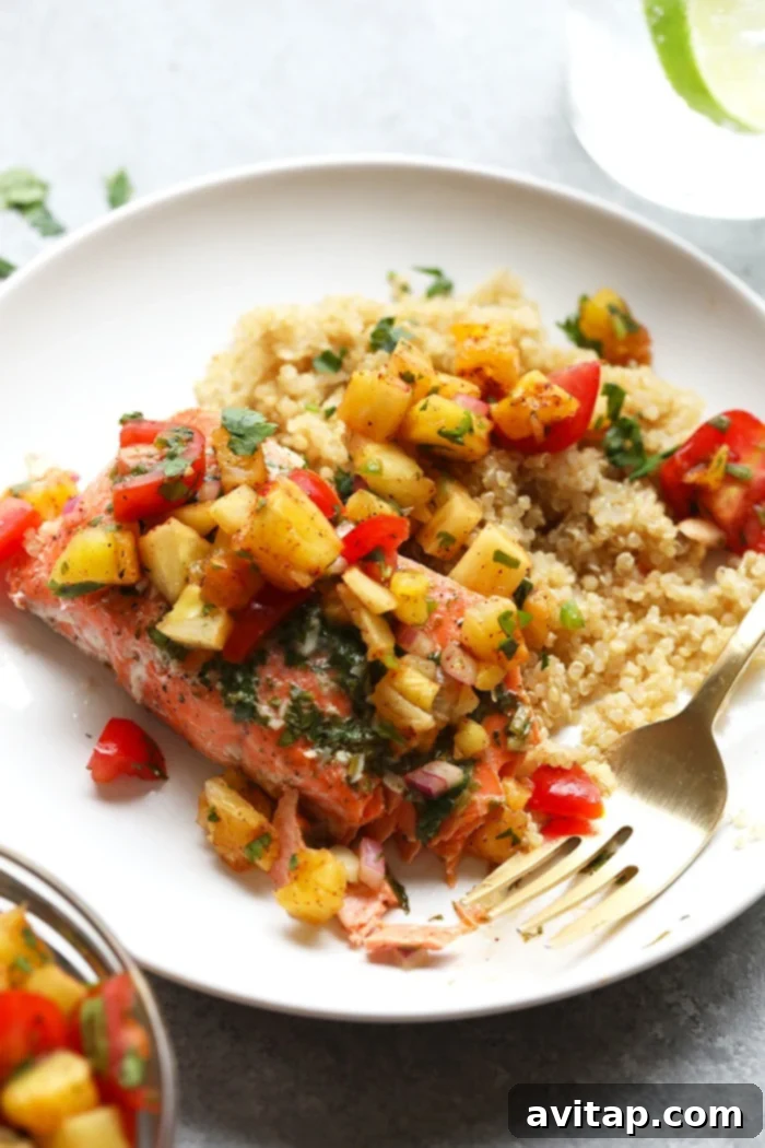Beautifully grilled salmon fillet on a white plate, garnished with a vibrant pineapple salsa.