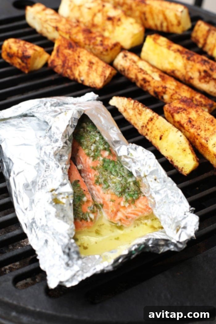 Grilled salmon in a foil packet alongside grilled pineapple, creating a vibrant summer meal.