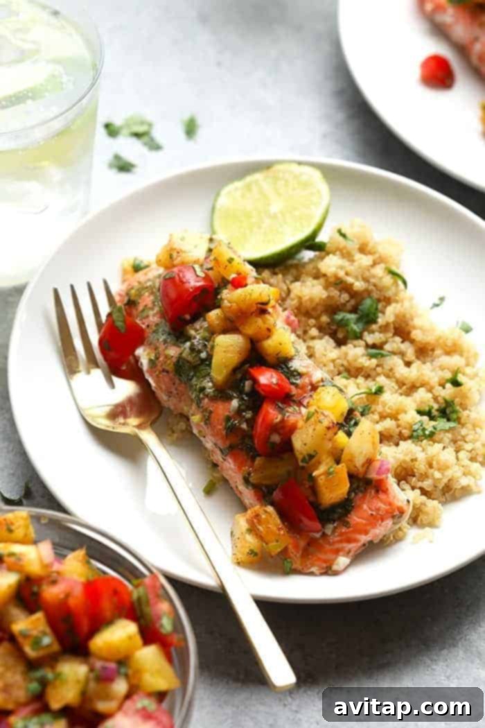 Flaky grilled salmon topped with fresh pineapple salsa, elegantly presented on a plate.