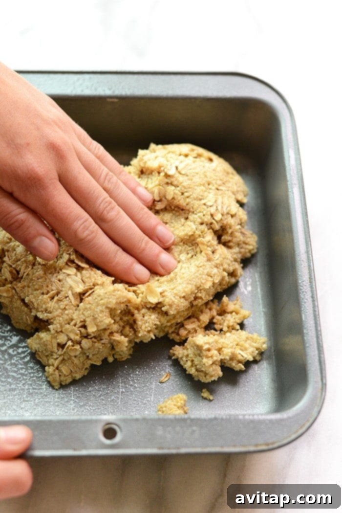 Pressing the almond flour crust mixture evenly into an 8x8-inch baking pan.