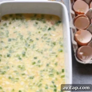 Egg mixture being poured over diced vegetables and ham in a casserole dish for Denver Omelette Bake.