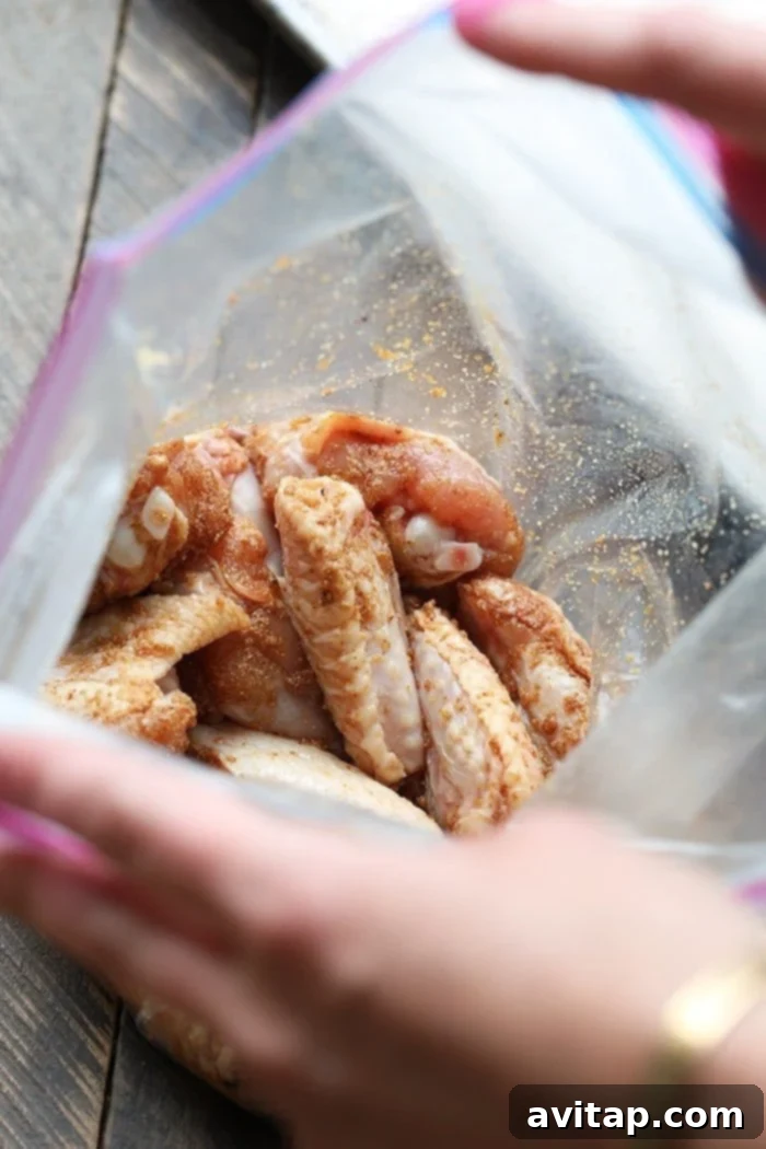 Unbaked chicken wings in a ziploc bag being tossed with spices, ready for baking.