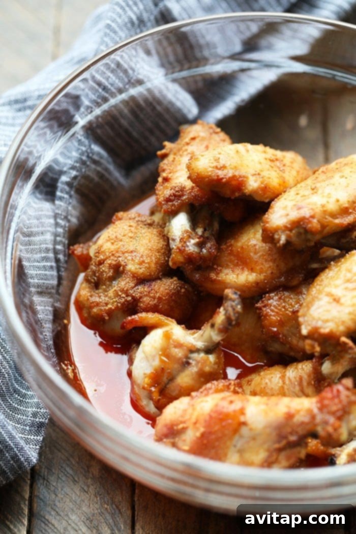 Buffalo chicken wings marinating in a glass bowl, absorbing the delicious dry rub and preparing for baking.