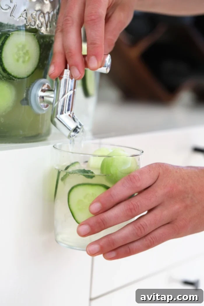 A chilled glass of cucumber vodka cocktail with cucumber slices, ready to be enjoyed on a hot summer day.