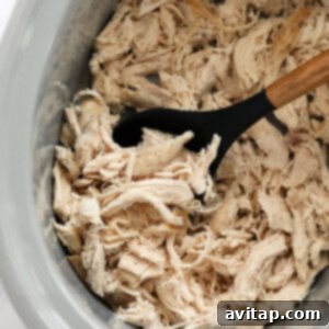 Shredded chicken in a slow cooker, perfectly cooked and ready to be used in various recipes.