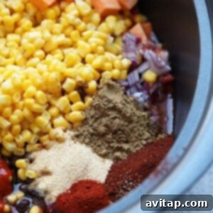 A slow cooker filled with ingredients for Mexican quinoa before cooking.