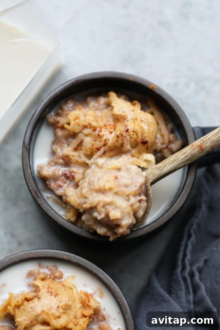 Close-up of steel cut oatmeal with shredded apple and a splash of almond milk, showcasing its creamy texture.