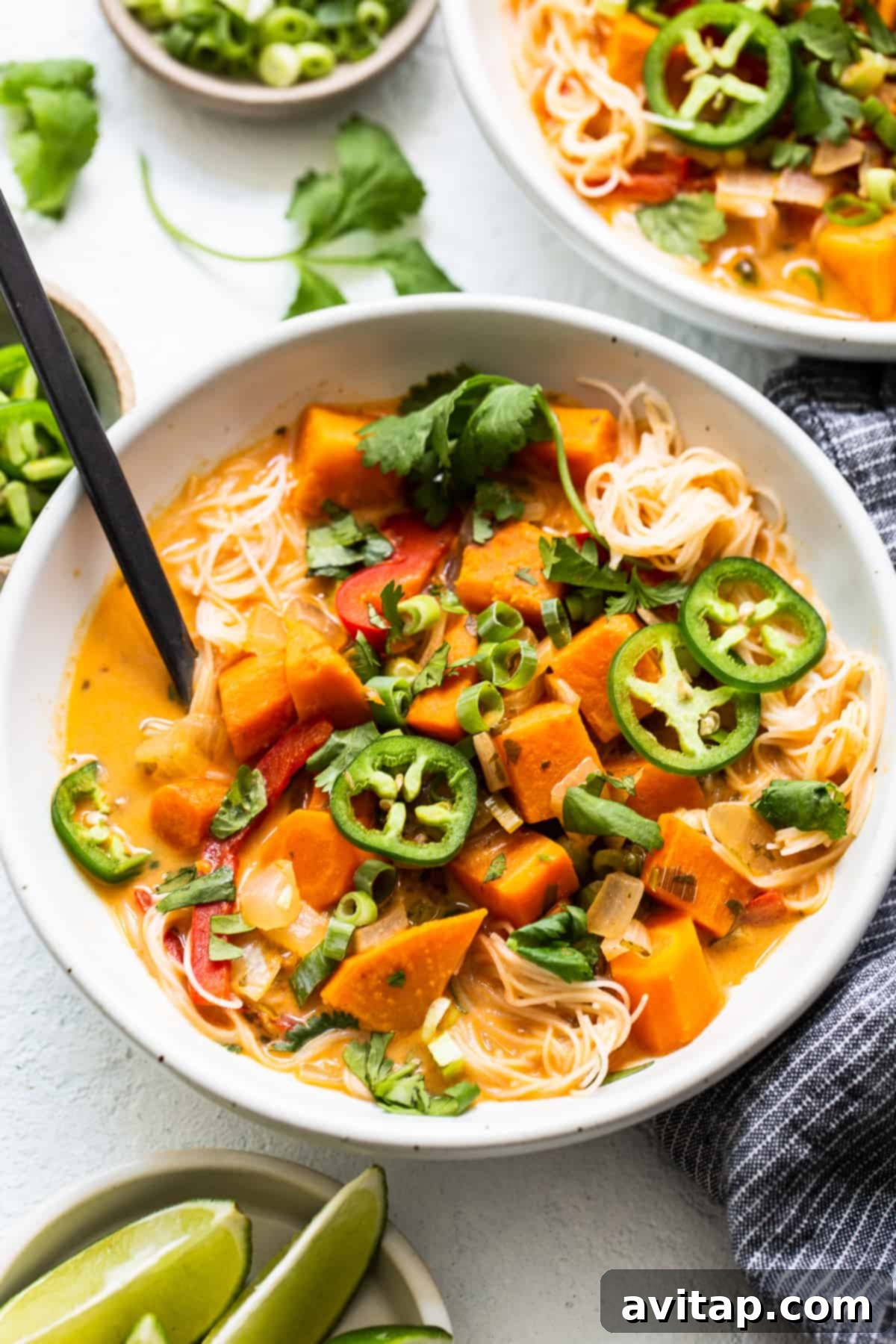 A vibrant bowl of homemade coconut curry soup, richly colored and garnished with fresh herbs, sitting on a wooden surface, ready to be enjoyed.