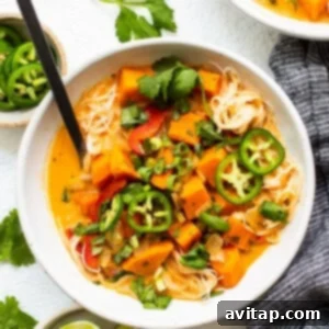 A beautifully presented bowl of Thai sweet potato noodle soup, garnished with fresh herbs and chili, ready to be enjoyed as a hearty meal.