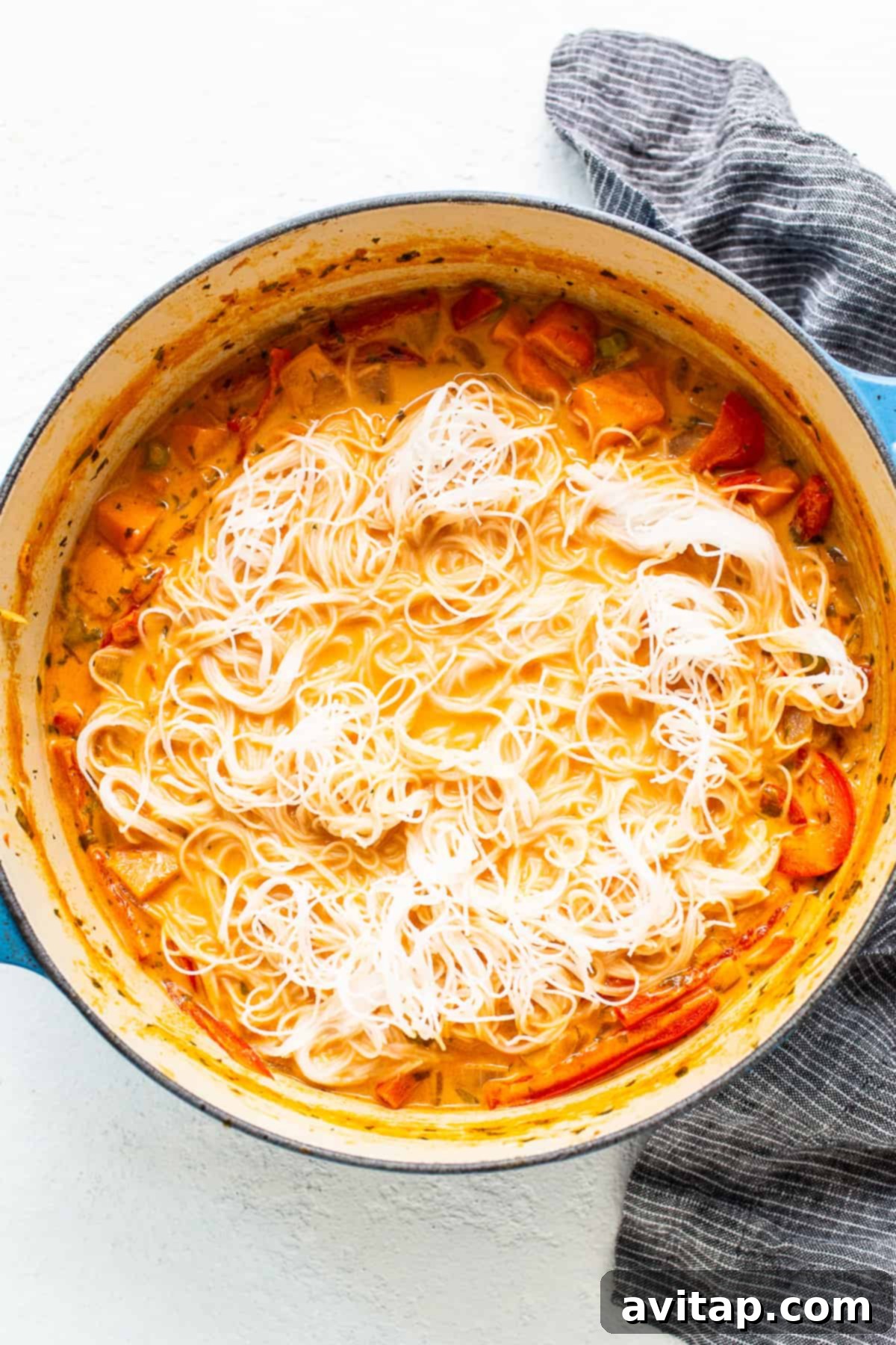A serving of the delicious coconut curry soup, highlighting the perfectly cooked rice noodles and an abundance of colorful, tender vegetables.