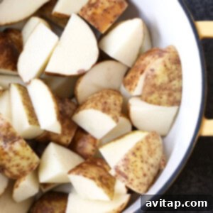 Raw potatoes in a pot filled with water, ready to be boiled for mashed potatoes.