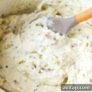 Healthy mashed potatoes being stirred with a wooden spoon in a yellow pot, showcasing the creamy texture.