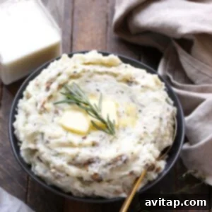 A bowl of healthy mashed potatoes, beautifully garnished with a pat of butter and sprigs of fresh rosemary.