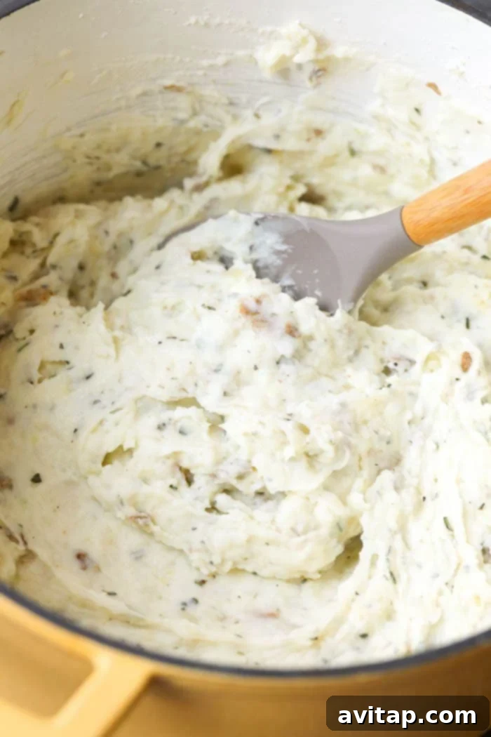 Healthy Mashed Potato Perfection 5 Healthy mashed potatoes being gently stirred with a wooden spoon in a large, inviting cooking pot, showcasing their creamy texture.