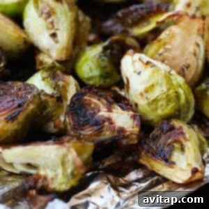 Grilled Brussels sprouts cooked on aluminum foil, showcasing a perfect char and tender interior.