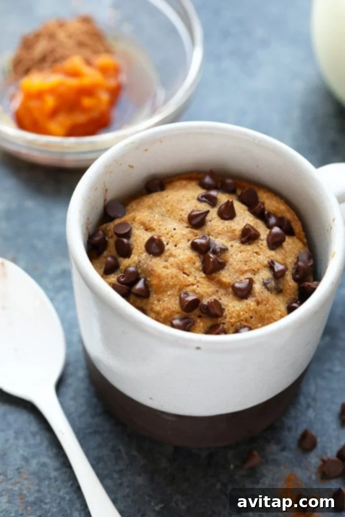 Wholesome Pumpkin Spice Mug Cake 4 A close-up of a freshly microwaved pumpkin mug cake, topped with a creamy chocolate pumpkin frosting.