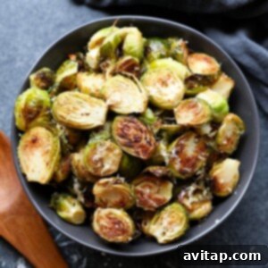 Roasted brussels sprouts with parmesan, served in a black bowl.