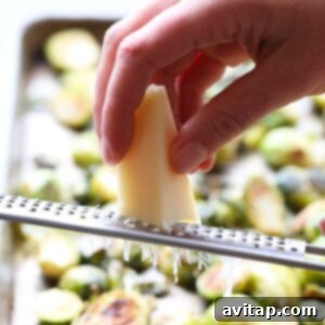 Crispy Parmesan Brussels Sprouts 4 a person grating parmesan on roasted brussel sprouts.