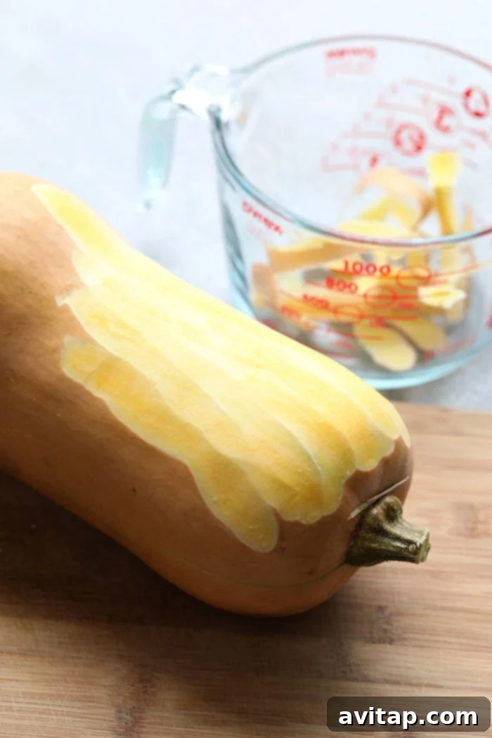 Freshly peeled butternut squash on a cutting board, ready for dicing.
