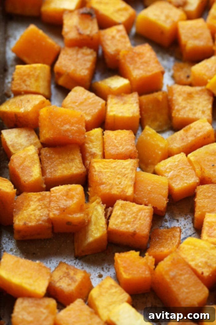 Golden-brown, perfectly roasted butternut squash cubes on a baking tray.