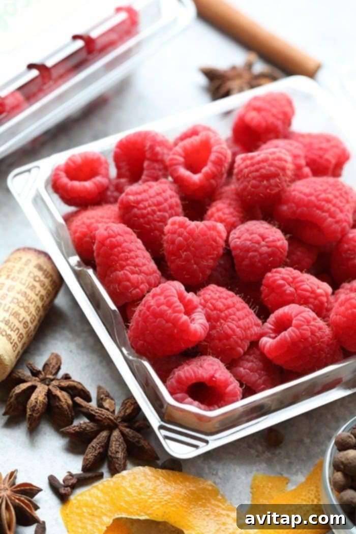 A close-up shot of plump, fresh raspberries, glistening with moisture, ready to be incorporated into the mulled wine recipe.