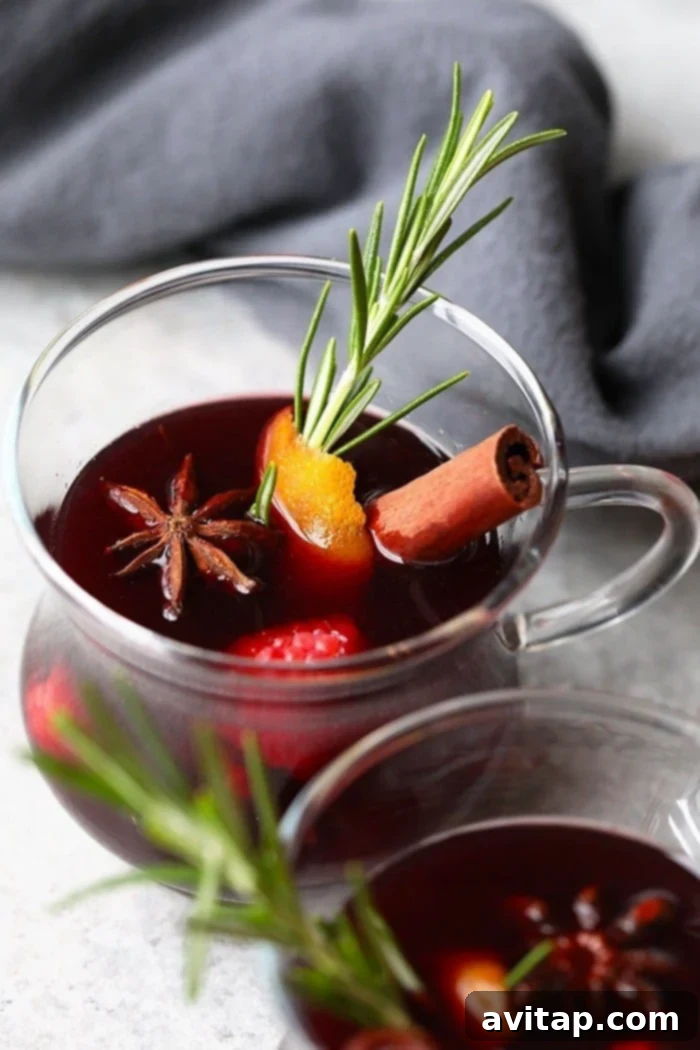 A close-up shot of a clear glass mug of steaming spiced mulled wine, garnished elegantly with a single star anise and a cinnamon stick, inviting warmth and comfort.
